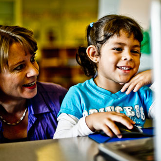 Teacher helping child on the computer
