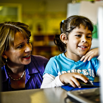 Teacher working with student at a computer station