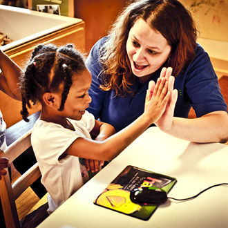Teacher giving student high-five at computer station