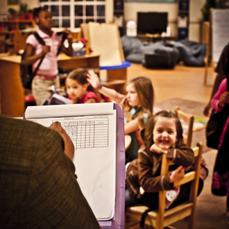 Teacher with clipboard and students in classroom