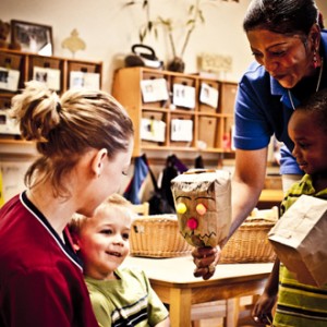 Teacher and child showing his mom his artwork.