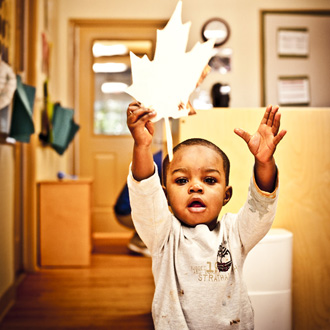 Child holding up cut-out leaf
