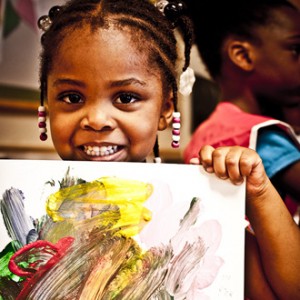 Child proudly holding up painting