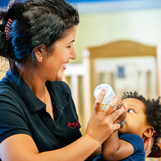 Child care provider feeding an infant