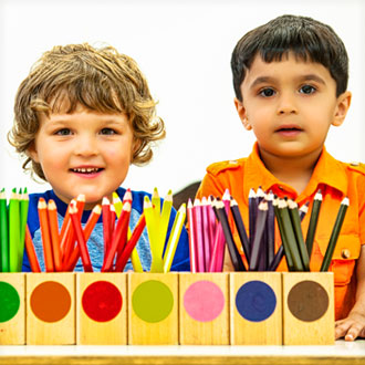 Two boys behind colored pencil boxes